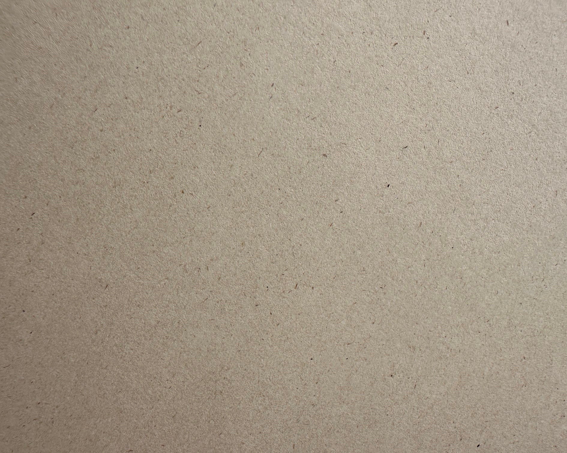 A close-up texture shot of a light brown eco paper surface with fine speckles and a matte finish.